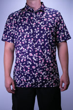 Person wearing a dark floral patterned shirt against a plain background