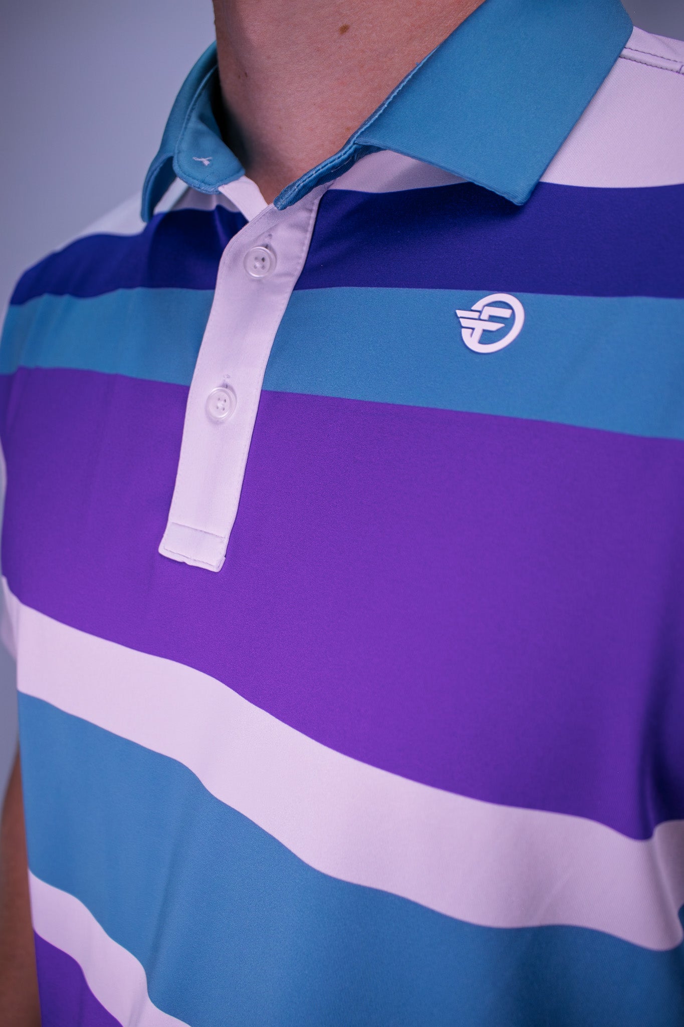 Close-up of a striped polo shirt with a logo on a plain background