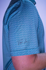Close-up of a person wearing a blue patterned shirt with a signature on a light purple background
