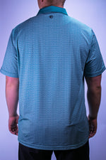 Teal patterned polo shirt worn by a person on a light purple background