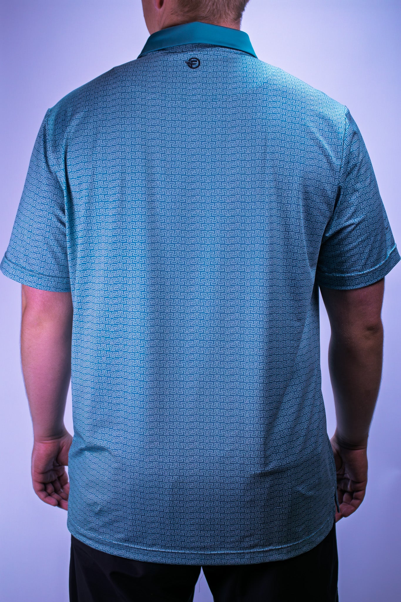 Teal patterned polo shirt worn by a person on a light purple background