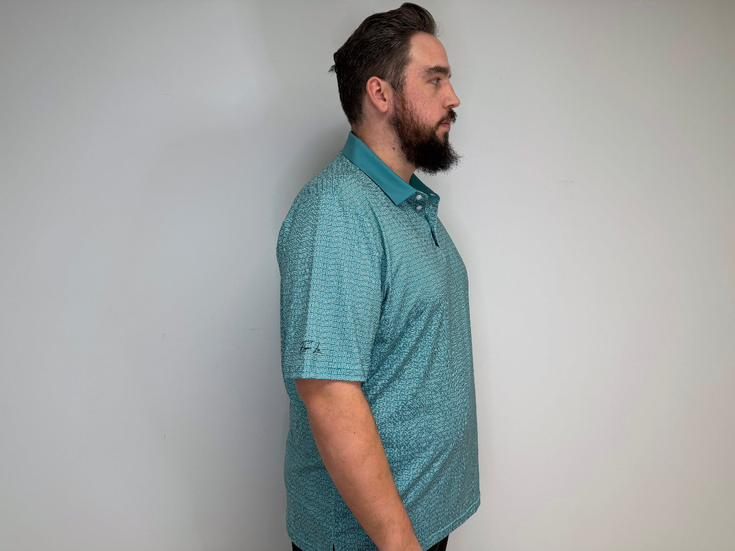 Man modeling a golf polo that is a blue base and white design