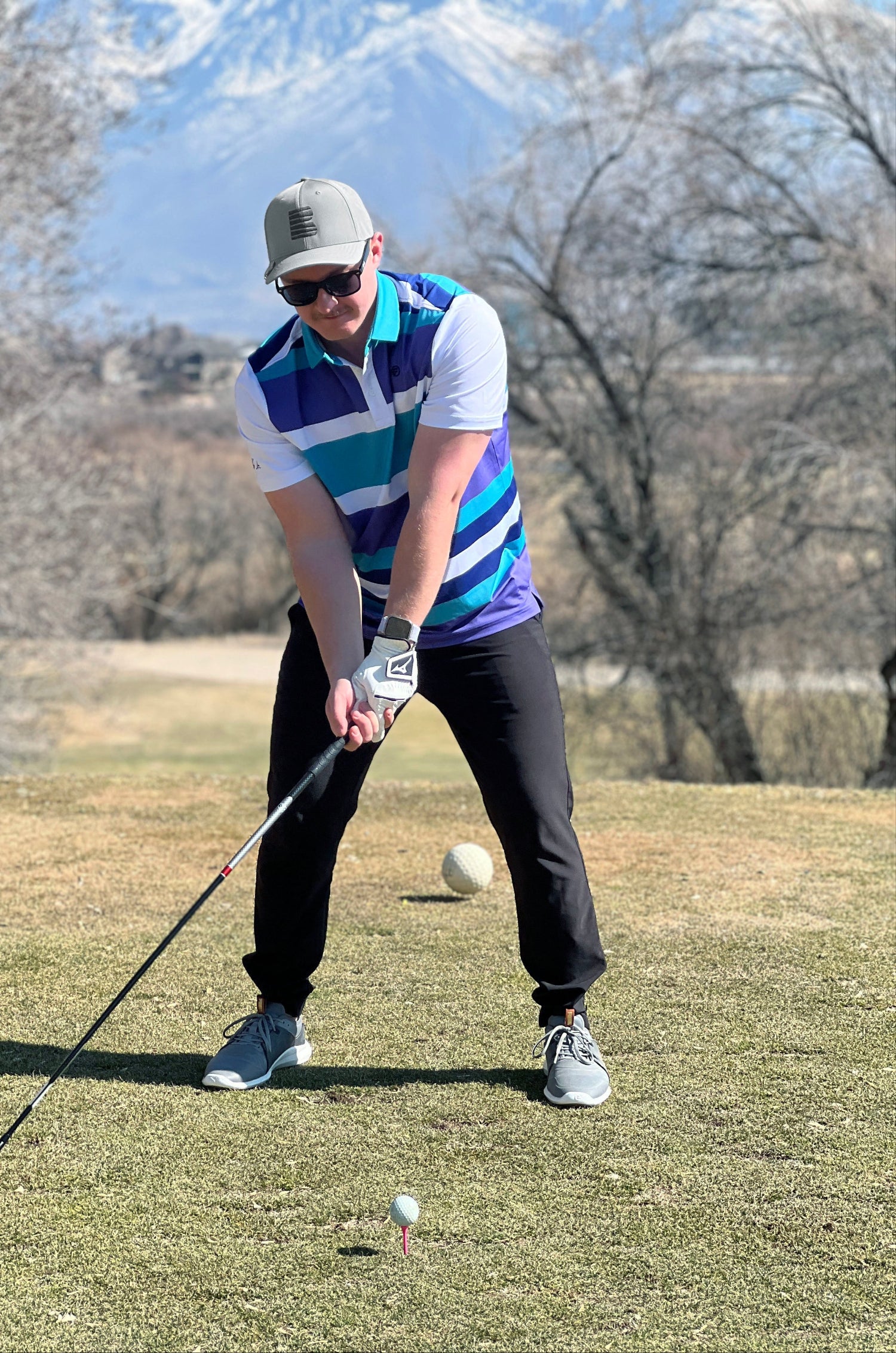 Man swinging a driver getting ready to hit the golf ball