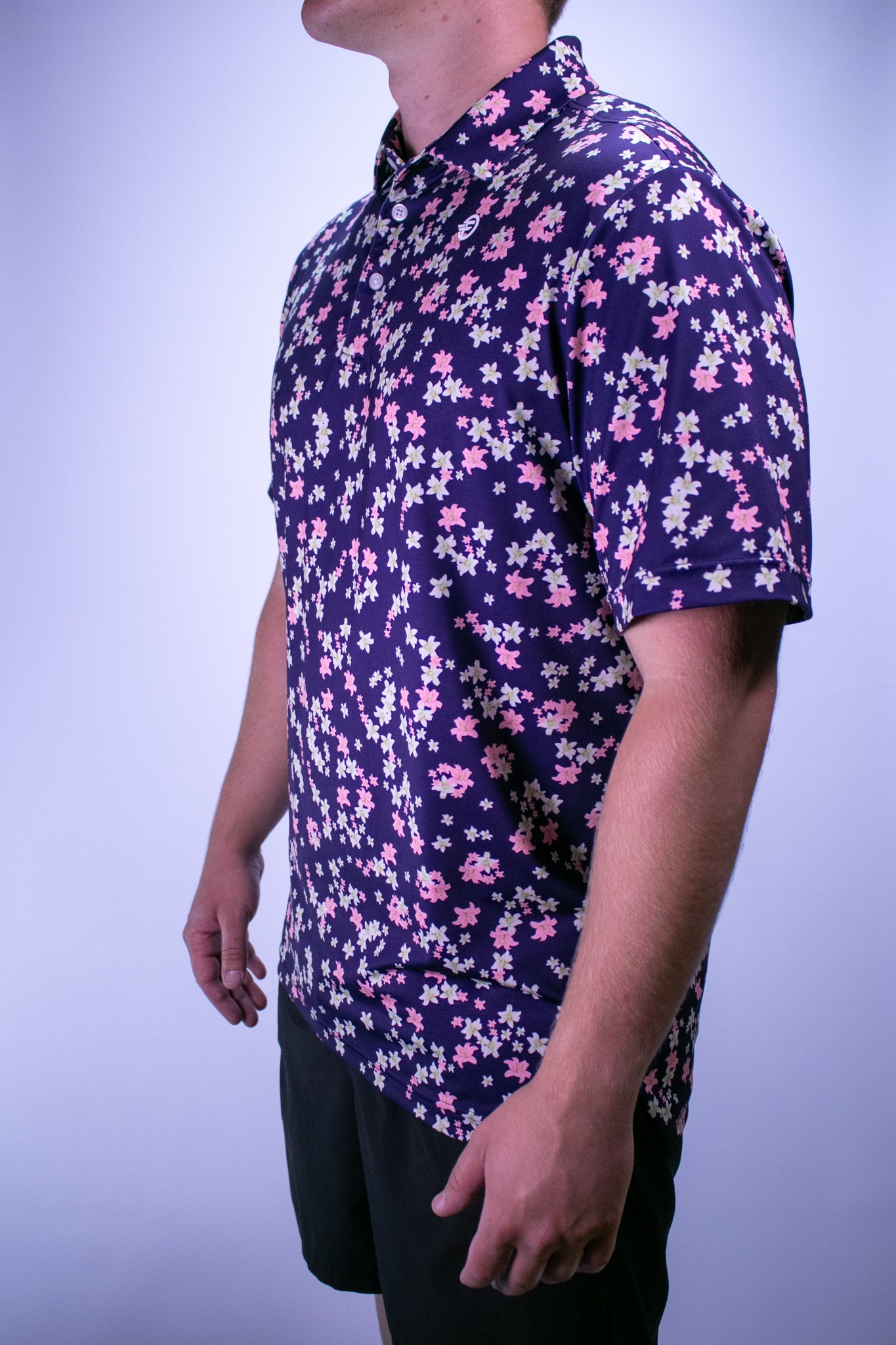 Person wearing a short-sleeve shirt with a floral pattern on a plain background