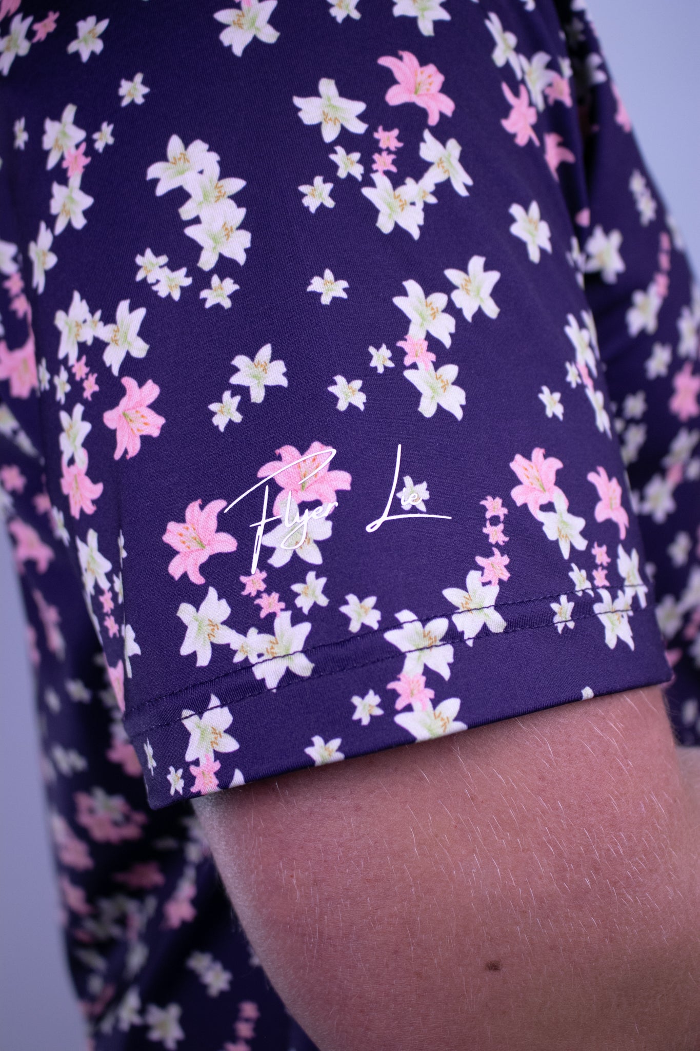 Navy shirt base with pink and white floral pattern and brand logo.