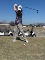 A guy swinging a Taylormade Sim 2 driver on a tee box. 2 golf carts in the back ground. 