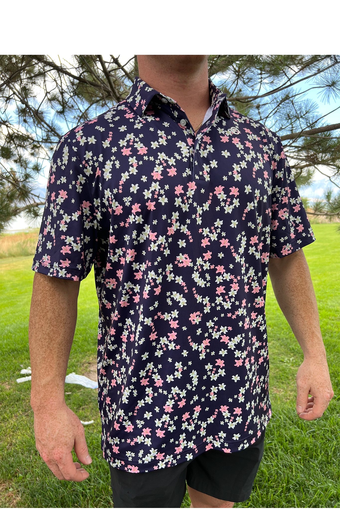 Person wearing a navy floral short-sleeve shirt outdoors.